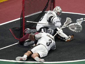 Calgary Roughnecks goalie Christian Del Bianco, back, stops a shot by Colorado Mammoth forward Zed Williams, who was knocked over by Calgary defender Jeff Cornwall.