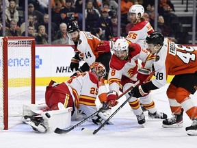 Calgary Flames goaltender Jacob Markstrom makes a save as defenceman Chris Tanev and Philadelphia Flyers forward Morgan Frost reach for the puck at Wells Fargo Center in Philadelphia on Saturday, Jan. 6, 2024.