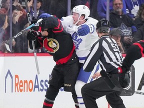 Morgan Rielly, centre, of the Toronto Maple Leafs cross-checks Ridly Greig, left, of the Ottawa Senators after his empty net goal in the third period at Canadian Tire Centre on Saturday, Feb. 10, 2024, in Ottawa.
