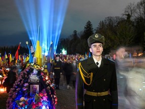 Ukrainian honour guards stand as a symbolic illumination called 'Ray of Memory' is seen over the graves of Ukrainian soldiers, who died in the war with Russia, at Lychakiv Cemetery in Lviv on February 23, 2024, on the second anniversary of Russia's invasion of Ukraine.