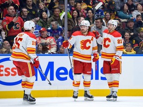 Calgary Flames defenceman Rasmus Andersson, centre, celebrates a goal against the Vancouver Canucks with Kevin Rooney, right, and Dryden Hunt at Rogers Arena in Vancouver on Saturday, March 23, 2024.