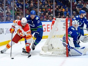Calgary Flames forward Martin Pospisil is chased by Vancouver Canucks defenceman Tyler Myers as Casey DeSmith guards the net at Rogers Arena in Vancouver on Saturday, March 23, 2024.