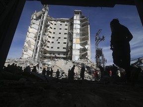 Palestinians walk by a residential building destroyed in an Israeli strike in Rafah, Gaza Strip on March 9, 2024.