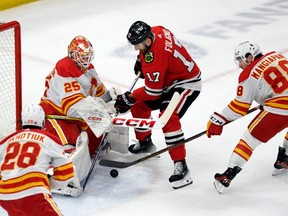 Calgary Flames goalie Jacob Markstrom and forward Andrew Mangiapane battle Chicago Blackhawks forward Nick Foligno for a loose puck at United Center in Chicago on Tuesday, March 26, 2024.