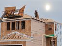 Construction workers build homes in the Livingstone development on the northern edge of Calgary on Tuesday, December 19, 2023.