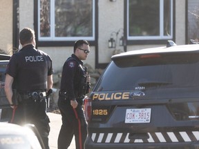 Calgary police officers are shown outside a home in the 200 block of Shawcliffe Circle S.W. on Monday. A death at the home has since been deemed non-criminal.
