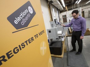 Elections Alberta business analyst Ryan Phillips demonstrates a high speed tabulator used to count advance polls in the May 2024 provincial general election on March 26, 2019. The province's Bill 20 seeks to ban such machines from being used in municipal elections.