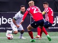 Cavalry FC midfielder Sergio Camargo tries to keep the ball from Atletico Ottawa midfielders Kristopher Twardek and Alberto Zapater at TD Place in Ottawa on Saturday, April 20, 2024.