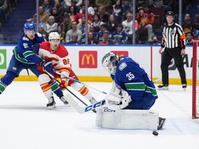 Vancouver Canucks goalie Thatcher Demko makes the save as defenceman Nikita Zadorov checks Flames forward Andrew Mangiapane at Rogers Arena in Vancouver on Tuesday, April 16, 2024.
