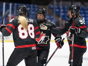 Canada's Renata Fast (14) celebrates her goal over Sweden with teammates Julia Gosling (88) and Danielle Serdachny (92) during second period quarterfinal action at the IIHF Women's World Hockey Championship in Utica, N.Y., Thursday, April 11, 2024.