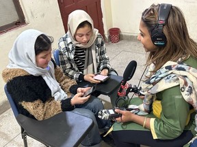 Motahera Sultani, left, and her best friend Nike Atei, right, show Molly Thomas the online platform they access on their phones for school.