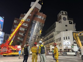 Rescue workers stand near the site of a leaning building in the aftermath of an earthquake in Hualien, eastern Taiwan, on Wednesday, April 3, 2024.