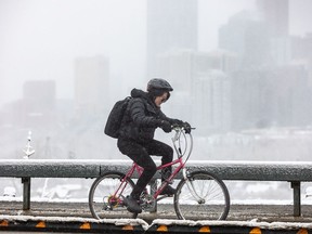 A cyclist braves the spring snowfall riding along the Crescent Heights trail in Calgary on Tuesday, April 16, 2024.