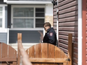 A police officer steps outside of a home on Redstone Common N.E. in Calgary, where a woman was killed on Sunday, April 21.