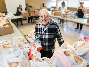 Volunteer Dorothy Bagan stands among bags of groceries to be distributed by the weekly bread market at the Kerby Centre in Calgary on Tuesday, April 2.