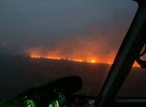 A helicopter with night vision flies near a wildfire burning southwest of Fort McMurray during the evening of May 15, 2024. Image supplied by Alberta Wildfire