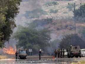 Israeli army forces deploy along a road near a blaze that erupted after rockets fired from south Lebanon landed near Kfar Szold in the Upper Galilee in northern Israel on June 14, 2024. Fallout from the Gaza war is regularly felt on the Israeli-Lebanon frontier, where deadly cross-border exchanges have escalated.