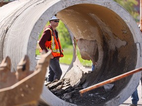 City of Calgary workers inspect the damaged water main pipe after it was removed at the repair site in Montgomery on Monday, June 10.