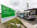 A Calgary Transit bus passes a sign advertising the route of the proposed LRT Green Line at the corner of 21st Avenue and 11th Street S.W.