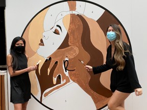 Amanda Lew Kee, left, and Victoria Radford of Radford Beauty in Toronto stand by a mural depicting a diversity of skin tones.