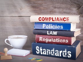 A stack of books on a desk with titles: Compliance, Policies, Law, Regulations, Standards. Legal issues to do with investing include estate planning, tax considerations, compliance with provincial securities laws and direct and passive investment issues.