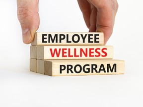 A hand stacks three wooden blocks with the words “Employee wellness program” printed on them. Younger workers, in particular, look for mental-health support from current and prospective employers.