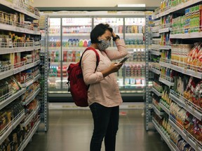 A woman holds her head while looking at food in a store. Supporters of Food Secure Canada believe not only in fighting hunger but supporting food producers and building a strong food supply.