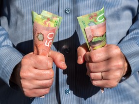 Two fists hold Canadian currency. Uncertainty versus yield are just a couple of the complexities investors need to weigh when deciding how much cash to hold right now.