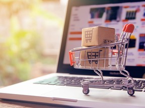 A photo illustration shows a miniature shopping cart with boxes sitting on a laptop keyboard. While larger deals – those exceeding $1 billion – have declined significantly from record activity in 2021, mid-market remains more active.