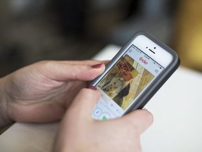 In this file photo, a young woman uses the Tinder online dating app on her smartphone. (Topher Seguin/Edmonton Journal/Postmedia Network)