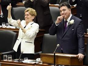 Ontario Finance Minister Charles Sousa, right, and Premier Kathleen Wynne get a standing ovation after announcing free universal health care to everyone over the age of 24 as part of the 2017 Ontario budget at Queen's Park in Toronto on Thursday, April 27, 2017.