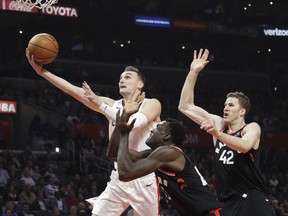 Los Angeles Clippers' Sam Dekker drives to the basket past Toronto Raptors' Pascal Siakam and Jakob Poeltl, right, on Dec. 11, 2017