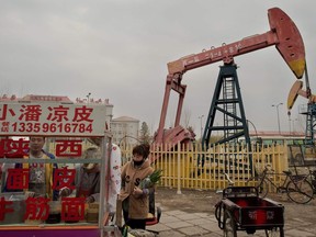 This picture taken on May 2, 2016 shows local residents buying noodle soup next to oil pumps in Daqing, Heilongjiang province.