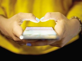 Young woman using cell phone to send text message on a social network at night.