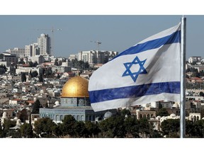 The Israeli flag flutters in front of the Dome of the Rock mosque and th city of Jerusalem, on December 1, 2017.  Two Israeli cabinet ministers said on November 30 that they hoped US President Donald Trump was about to move his country's embassy from Tel Aviv to Jerusalem, as a decision deadline neared. The issue is deeply controversial. Shifting the building could be seen as a de facto recognition of Israel's claim over the whole city, including predominantly Palestinian east Jerusalem.