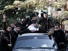 Palestinian militants from the Ezzedine al-Qassam Brigades, the armed wing of the Hamas movement, sit on a car with the body of their comrade Mohamed al-Safadi, who was killed the previous day in an Israeli air strike, during his funeral in Gaza City on December 9, 2017.