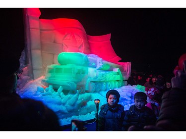 Children pose for a photo before an ice sculpture depicting a Hwasong-15 intercontinental ballistic missile (ICBM) and self-propelled launcher, as people mark the new year at the Pyongyang Ice Sculpture Festival on Kim Il Sung Square in Pyongyang on December 31, 2017.