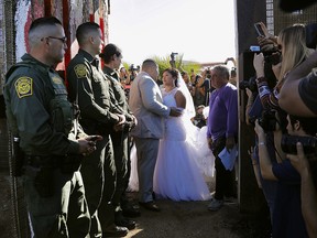 In this Nov. 18, 2017, photo, Brian Houston, of Rancho San Diego, centre left, and Evelia Reyes, right, of Tijuana, Mexico, look at each other in their wedding at the "Door of Hope," part of the border fence between the U.S. and Mexico.