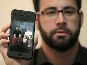 Jamey Anderson holds a photo on his phone of himself, bottom left, at the Word of Faith Christian School with classmates, from left, Liam, Risa Burgeson Pires, and Christopher Davies, and teachers Lisa Brown, top left, and Marty Roper, top right, during an interview in Charlotte, N.C., Monday, Dec. 11, 2017. Throughout his adolescence, Anderson says he was singled out as a rebel and suffered some of the most brutal treatment in the church. Among his transgressions: making a funny face at a classmate.
