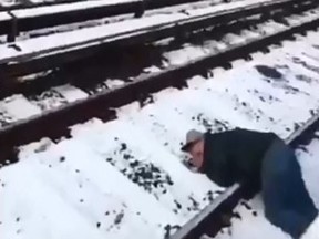 In this screenshot, a man lies unconscious on the tracks at a Brooklyn subway station.