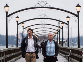 A pigeon flies past Prime Minister Justin Trudeau, left, as he and South Surrey-White Rock Liberal byelection candidate Gordie Hogg walk along the pier in White Rock, B.C., on December 2, 2017.