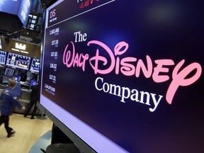 FILE - In this Aug. 8, 2017, file photo, The Walt Disney Co. logo appears on a screen above the floor of the New York Stock Exchange. Disney is buying a large part of the Murdoch family's 21st Century Fox in a $52.4 billion deal, announced Thursday, Dec. 14, including film and television studios, cable and international TV businesses as it tries to meet competition from technology companies in the entertainment business.