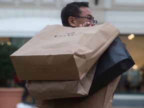 A man carries shopping bags of Boxing Day sale purchases at the McArthur Glen Designer Outlet mall, in Richmond, B.C., on Tuesday, December 26, 2017.