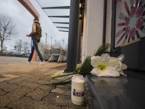 A man lays down flowers at the entrance of the drugstore in Kandel, Germany, Thursday, Dec. 28, 2017.