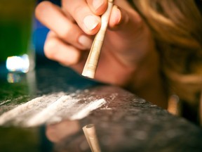 In this stock photo, a young woman snorts cocaine with a bill.