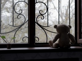 In this stock photo, a teddy bear sits in a window.