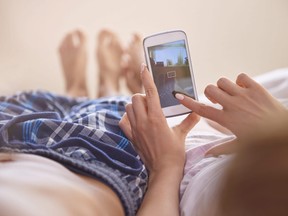 In this stock photo, a couple sit on a bed half-dressed as they look at a cellphone.