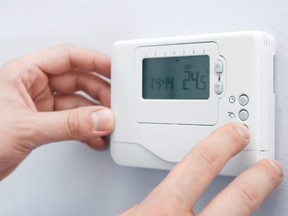 In this stock photo, a man adjusts a digital thermostat.