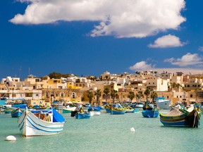 Colorful, traditional fishing boats against the backdrop of Marsaxlokk village in the mediterranean island of Malta. (Getty Images)
