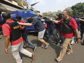 In this Monday, May 22, 2017, file photo, police officers escort men arrested in a raid on a gay sauna at North Jakarta police headquarters in Jakarta, Indonesia.